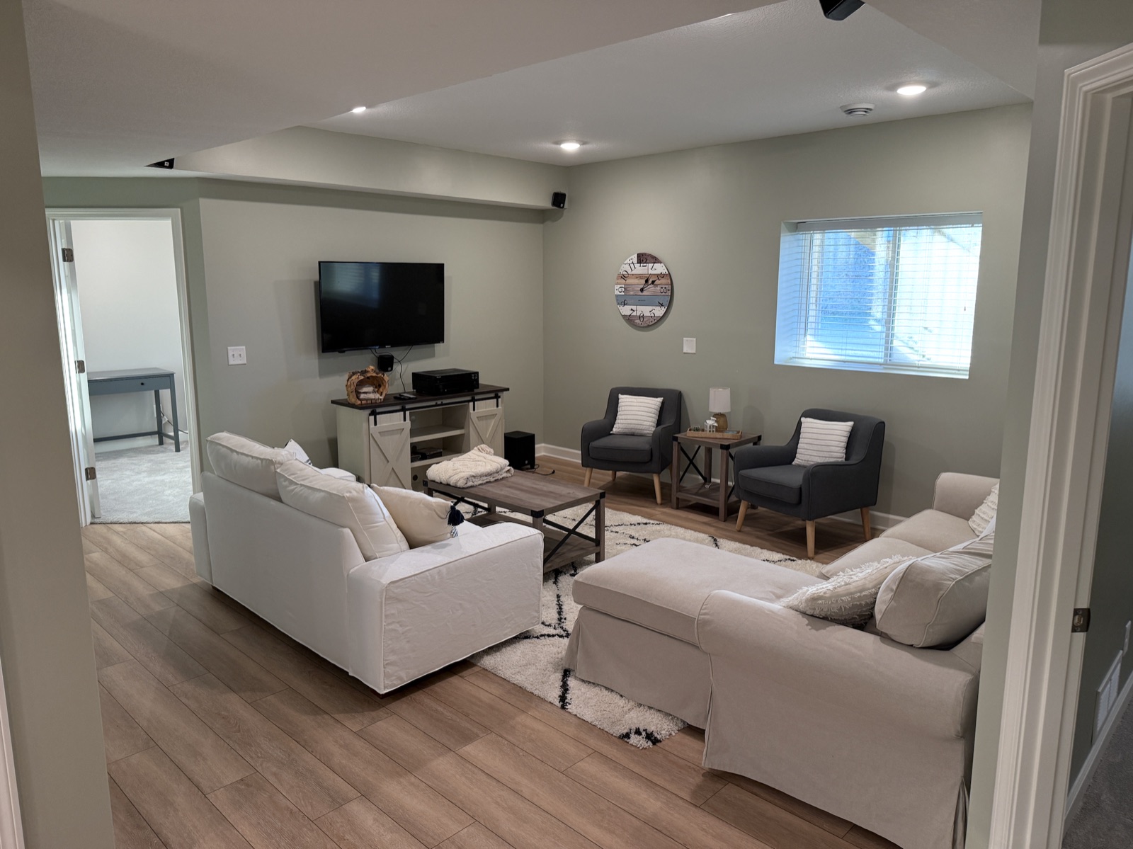 A finished, freshly painted basement living room with smooth walls and trim