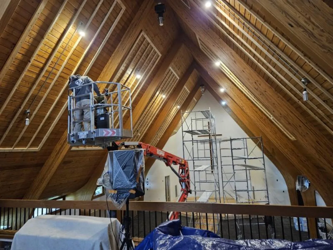 A worker on a hydraulic lift preparing a ceiling for paint