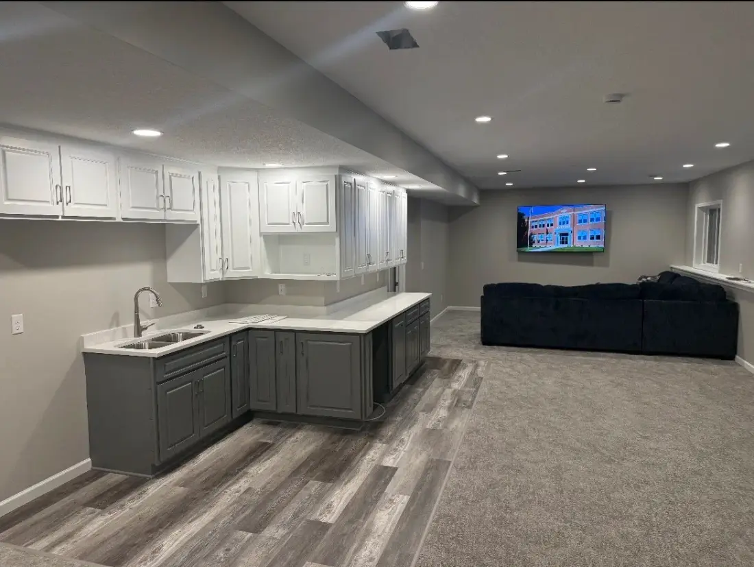 The same basement finished with a smooth drywall ceiling, recessed lighting, cabinetry, and flooring
