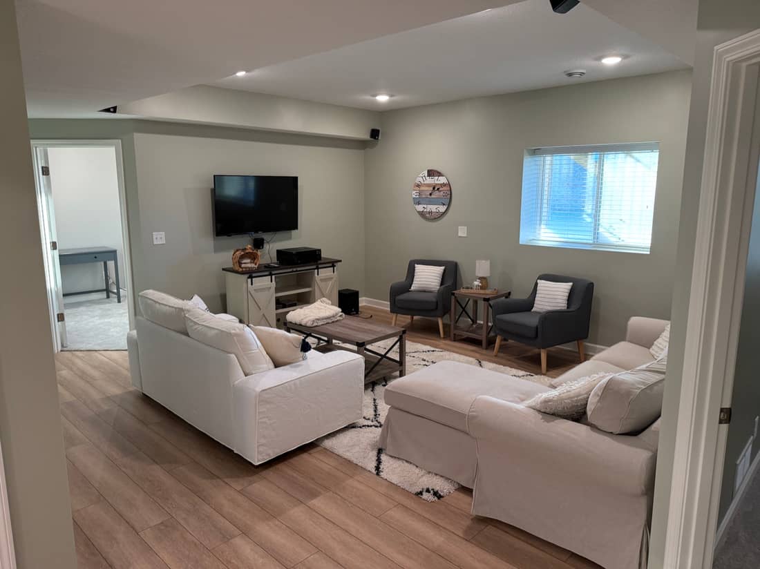 A finished, freshly painted basement living room with smooth walls and trim